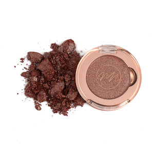 A pan of brownish silver eye shadow with a pile of loose powder scattered in front of it.