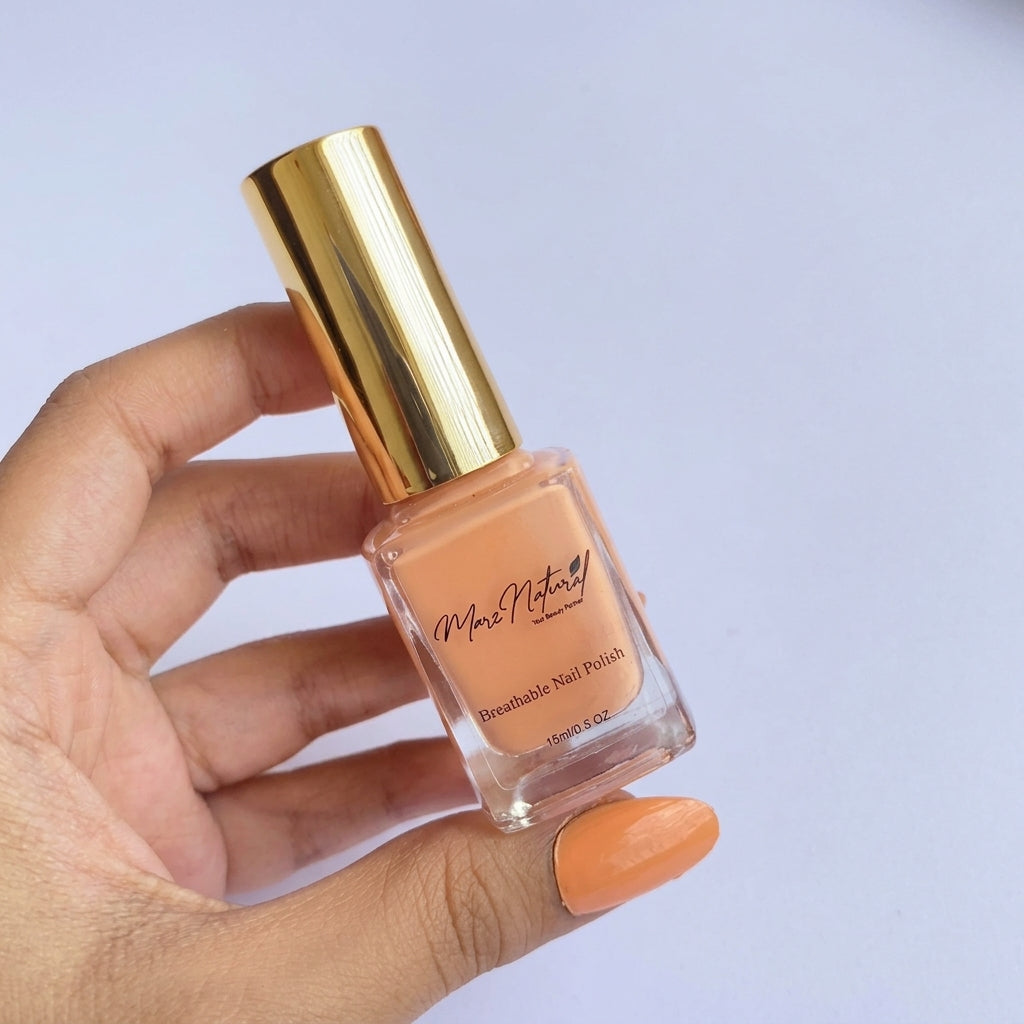 A hand holding a bottle of peach-colored breathable nail polish with a shiny gold cap, set against a light lavender background.