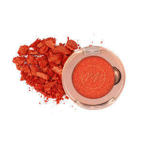 A single pan of rusty orange colored eyeshadow with a velvety texture, shown both in a compact form and as a loose powder pile.