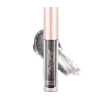 A pink-bottled liquid eye shadow with a black glittery formula, shown with a applicator wand coated in the product.